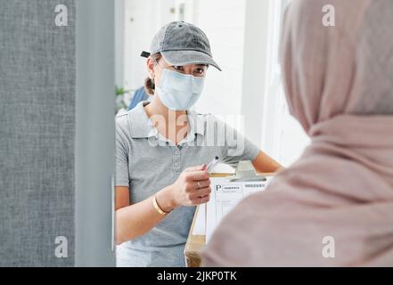 Ist das genau das, was Sie bestellt haben? Eine attraktive junge Frau, die zu Hause steht und einem Kunden eine Schachtel liefert. Stockfoto