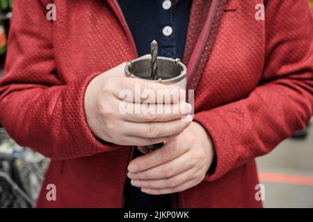 Eine Frau im Geschäft kauft eine Bohrmaschine, um Nischen für Steckdosen zu bohren. Nahaufnahme Stockfoto