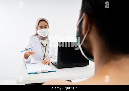 Arzt in einem Hijab fragt einen männlichen zukünftigen Hadsch-Pilger Stockfoto