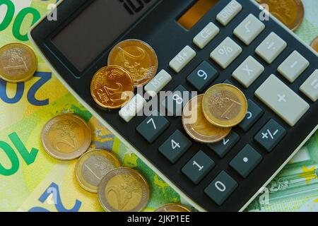 Neuberechnung von Geld. Taschenrechner und Euro-Münzen auf Euro-Banknoten Hintergrund.Steuern in EU-Ländern.Euro-Währung.Budgetzuweisung. Stockfoto