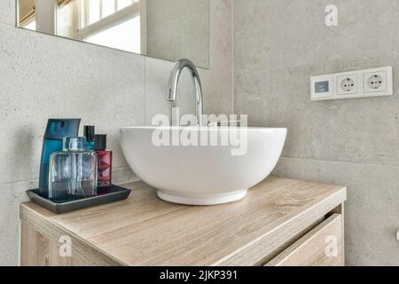 Interieur des modernen Badezimmers mit Badewanne und Waschbecken in Holztheke mit Holzregal ausgestattet Stockfoto