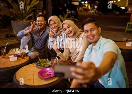 Ein glücklicher muslimischer Freund genießt es, iftar zu Abend zu essen und Selfie zu machen Stockfoto