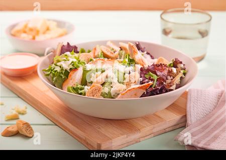 Eine Nahaufnahme des leckeren caesar Salats auf einem weißen Teller auf einem Holzbrett Stockfoto