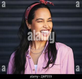 Shes eine verspielte Seele. Beschnittenes Porträt einer attraktiven jungen Frau, die vor grauem Hintergrund spielerisch zwinkert. Stockfoto