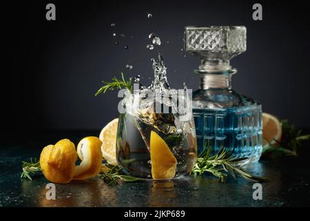Gin Tonic Cocktail mit Zitrone und Rosmarin. Zitronenscheibe in Glas mit einem Cocktail fallen. Stockfoto