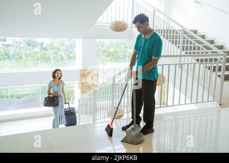 Der Hausmeister fegt, als weibliche Gäste im Hotel Treppen steigen Stockfoto