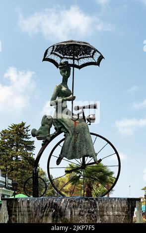 Die Bronzestatue auf dem Brunnen, der eine Dame mit Welpe und Regenschirm auf dem Retro-Fahrrad im Park von Batumi, Georgia, darstellt Stockfoto