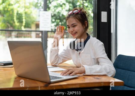 Online-Bildung, E-Learning. Junge Frau, die aus der Ferne studiert, mit einem Laptop unterwegs ist und sich zu Hause Online-Webinare anhört Stockfoto