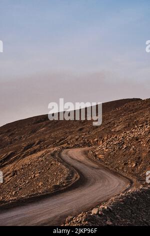 Eine vertikale Aufnahme einer kurvigen Straße auf dem felsigen Hang. Stockfoto