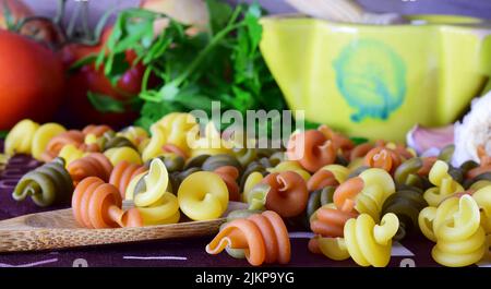 Eine Nahaufnahme von farbigen Nudeln und Tomaten mit anderen Zutaten. Gesunde Ernährung. Stockfoto