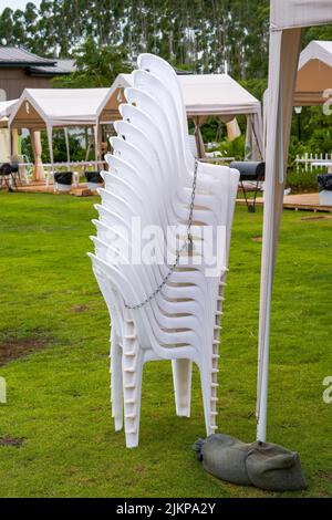 Stapel von weißen Plastikstühlen bei einer Party im Freien Stockfoto