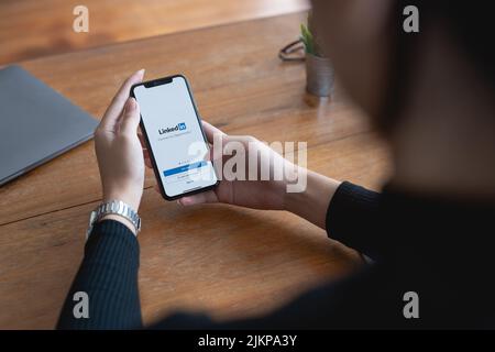 CHIANG MAI, THAILAND - 29. JUNI 2022 : Frau mit iPhone Eröffnung der Linkedin App. LinkedIn ist eine Social-Media-Website, die sich auf Business-Networking spezialisiert hat Stockfoto