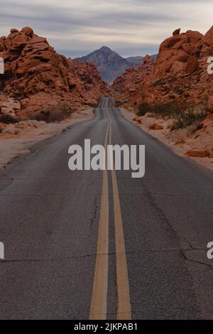 Eine vertikale Aufnahme einer zweifachen, gelben Asphaltstraße durch eine felsige Landschaft Stockfoto