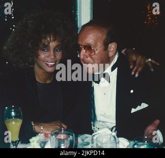 Whitney Houston und Clive Davis nehmen am 17. März 1990 an der Arista AIDS Party in Tavern on the Green in New York City Teil. Foto: Henry McGee/MediaPunch Stockfoto