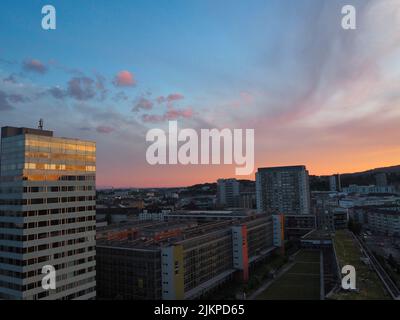 Panoramablick auf die Stadt Linz im Sonnenuntergang mit schönen kleinen Wolken, die Gebäude einer Skyline der Stadt im Sonnenuntergang reflektieren, belebte Straßen am Abend Stockfoto