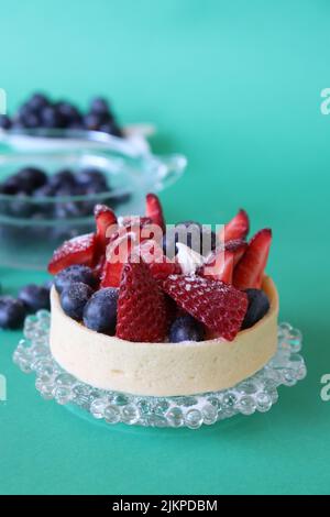 Eine köstliche Obsttarte mit Beeren auf grünem Hintergrund Stockfoto
