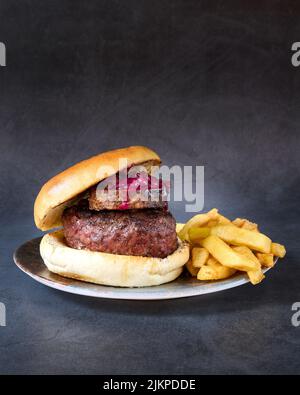 Eine vertikale Aufnahme eines Wagyu-Rindfleischburgers mit pommes auf einem Teller. Stockfoto