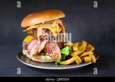 Eine Nahaufnahme eines bayerischen Burgers mit doppeltem Rindfleisch und pommes auf einem Teller. Stockfoto