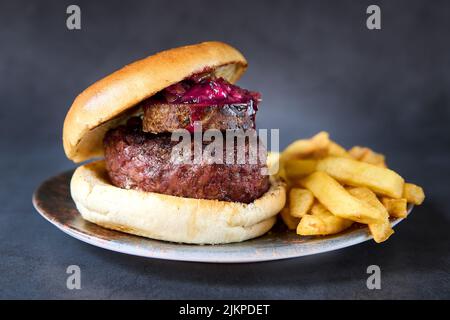 Eine vertikale Aufnahme eines Wagyu-Rindfleischburgers mit pommes auf einem Teller. Stockfoto