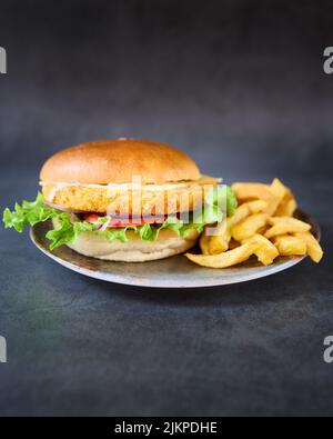 Eine vertikale Aufnahme eines Chicken Burger mit pommes auf einem Teller. Stockfoto