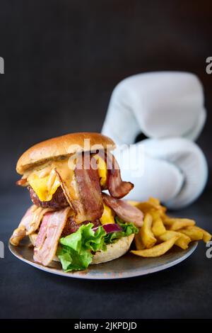 Vertikaler Schuss bayerischer Burger mit doppeltem Rindfleisch und pommes auf einem Teller. Stockfoto