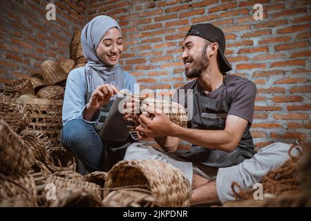Handwerker, der mit einer Frau in Hijab Wasserhyazinthe bastelt Stockfoto