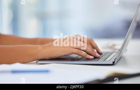 Dieser neue Laptop war eine Freude zu benutzen. Ein anonymer sitzt auf ihrem Schreibtisch und tippt auf ihrem Laptop. Stockfoto
