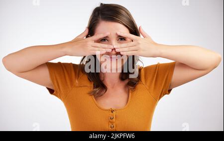 Können Sie mich sehen. Studioaufnahme einer jungen Frau, die ihr Gesicht mit den Händen vor weißem Hintergrund bedeckt. Stockfoto