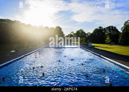 Hannover, Deutschland. 03. August 2022. Am frühen Morgen schwimmen Schwimmer im Licht der aufgehenden Sonne im Außenpool von Annabad ihre Bahnen. Quelle: Julian Stratenschulte/dpa/Alamy Live News Stockfoto