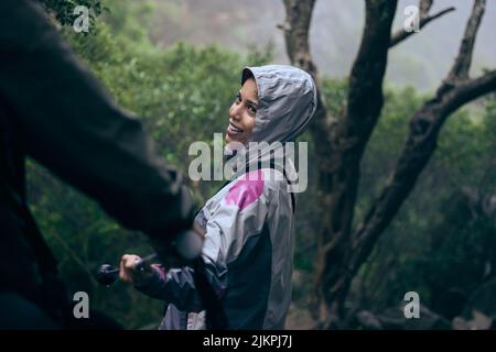 Folgt mir, Baby. Eine attraktive junge Frau, die ihren Freund auf eine morgendliche Wanderung durch die Berge führt. Stockfoto