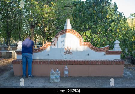 La Codosera, Spanien - 21.. August 2021: Heiligtum unserer Lieben Frau von Chandavila. Lokaler Mann, der Flaschen am heiligen Brunnen füllt Stockfoto