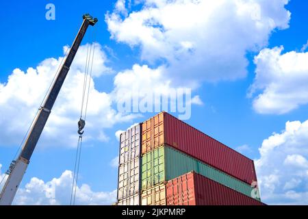 High-up-Ansicht Industrie-Container-Lagerung und Kran in Lagerterminal für die Verpackung von Produkten für den Transport auf blauem Himmel Hintergrund Stockfoto