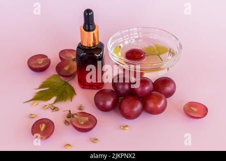 Eine Flasche gefärbtes Glas mit einem Naturkosmetik für die Gesichtspflege. Molke auf Basis von Aprikosenkernen. Bio-Öl. Rosa Hintergrund Stockfoto