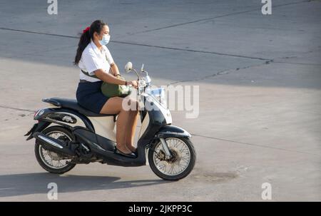 SAMUT PRAKAN, THAILAND, MAI 30 2022, Eine Frau mit Gesichtsmaske fährt ein Motorrad Stockfoto