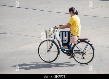 SAMUT PRAKAN, THAILAND, MAI 30 2022, Eine Frau fährt auf einem Fahrrad auf der Stadtstraße. Stockfoto