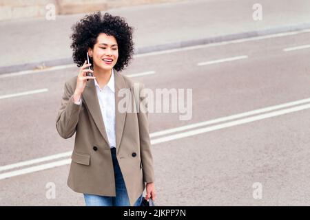 Frau überquert die Straße und telefoniert Stockfoto