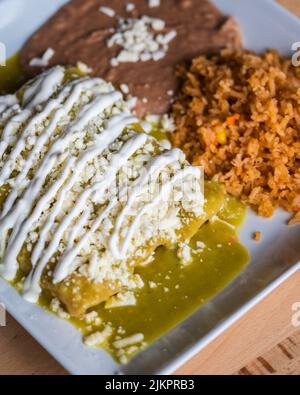 Eine vertikale Aufnahme eines mexikanischen Gerichts mit Enchiladas Verdes mit Reis und Bohnen Stockfoto