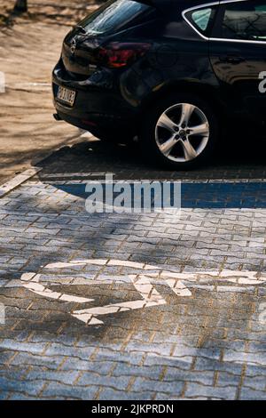 Eine vertikale Aufnahme eines Parkplatzes für behinderte Fahrer durch ein geparktes Auto im Bezirk Stare Zegrze. Posen. Stockfoto