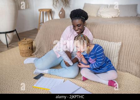 Dunkelhäutige Frau, die einem Mädchen mit Down-Syndrom etwas vorliest Stockfoto