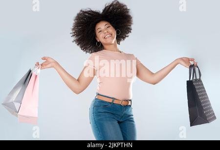 Schnäppchen lassen mich vor Freude springen. Studioporträt einer jungen Frau, die beim Tragen einer Einkaufstasche springt. Stockfoto