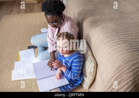 Ein Mädchen mit Down-Syndrom, das mit ihrem Lehrer etwas liest Stockfoto