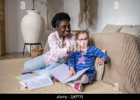 Ein Mädchen mit Down-Syndrom, das mit ihrem Lehrer etwas liest Stockfoto