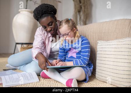 Ein Mädchen mit Down-Syndrom, das mit ihrem Lehrer etwas liest Stockfoto