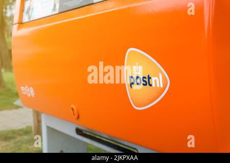 PostNL orangefarbener Briefkasten mit Logo-Nahaufnahme. Mailbox des niederländischen Postdienstleisters. Hertogenbosch, Niederlande - 7. Mai 2022. Stockfoto