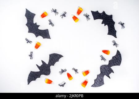 Halloween Rahmen Hintergrund. Fledermaus- und Spinnendekorationen mit traditionellem Trick o Treat Candy Corn auf weißem Hintergrund. Halloween Grußkarte. Flat la Stockfoto