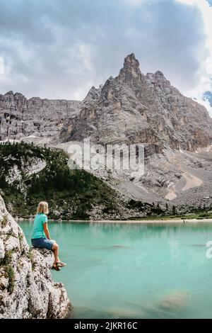 Weibliche Backpacker genießen türkisfarbenen Lago di Sorapiss Bergsee, Dolomiten Berge, Italien.Aktive Menschen in der Natur.Kalksteingipfel, Schluchten, Kristall Stockfoto