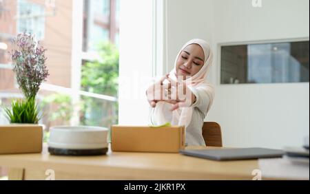 Entspannende asiatische muslimische Frau Kleinunternehmerin zu Hause. Stockfoto