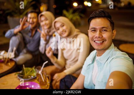 Ein glücklicher muslimischer Freund genießt es, iftar zu Abend zu essen und Selfie zu machen Stockfoto