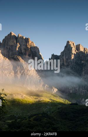 Die Morgenwolken schweben in einem sanften Lichtbild über den felsigen Berggipfeln Stockfoto