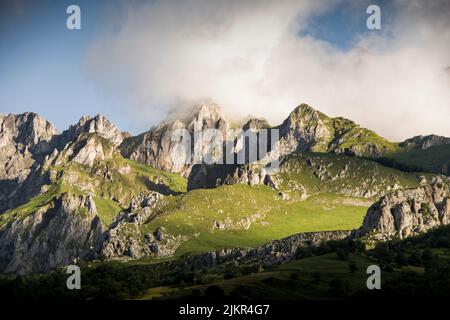 Die Morgenwolken schweben in einem sanften Lichtbild über den felsigen Berggipfeln Stockfoto